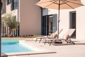 a patio with two chairs and an umbrella next to a pool at Andrea Deluxe Apartment with Pool in Mali Lošinj