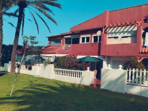 a red house with a white fence and a palm tree at Buganvilla 56 in Roquetas de Mar