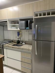 una cucina con frigorifero in acciaio inossidabile e mobili bianchi di Apartamento Inteiro 2 Quartos a São José dos Campos