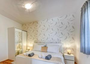 a bedroom with a white bed with a wall with a mirror at Villa Lara, Family Retreat with Sea View & Pool in Sveti Filip i Jakov +27 photos