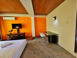 a bedroom with orange walls and a desk and a bed at Las Luciernagas Hotel in Flores