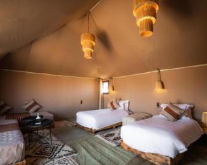 Habitación con 2 camas en una tienda con luces en Africa Luxury Camp, en Merzouga