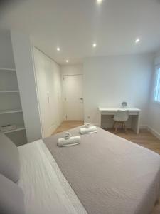 a bedroom with a bed with two towels on it at Apartamentos Mar de la Concha in Vilagarcia de Arousa +119 photos