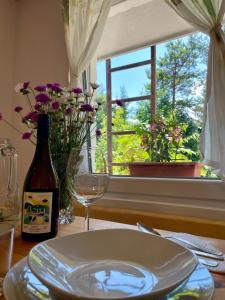 a table with a plate and a bottle of wine and a window at The Wood Nest Apartment in Borovnica