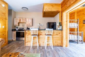 a kitchen with two bar stools in a log cabin at Relaxing Getaway at Smoky Arcade & Resort Pool in Pigeon Forge