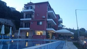 a pink building with a pool in front of it at Katerina Lefkada in Vasiliki