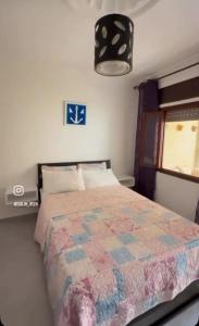 a bedroom with a bed with a quilt on it at Firras Mdiq in M'diq