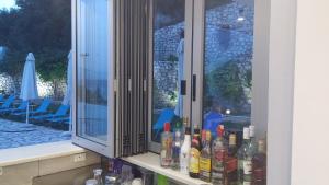 a bunch of bottles on a counter in front of a window at Katerina Lefkada in Vasiliki