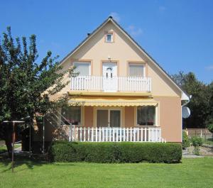 a large house with a white balcony on top of it at Fanni Guest House in Balatonvilágos