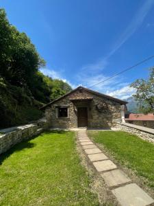 a small stone house with a grass yard in front of it at Cabaña Los Tejos in San Pedro