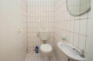 ein weiß gefliestes Bad mit einem WC und einem Waschbecken in der Unterkunft City Apartment Papenburg in Papenburg