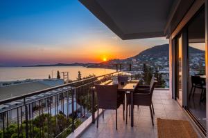 a balcony with a table and chairs and a sunset at Era Suites Lagonisi in Kalívia Thorikoú