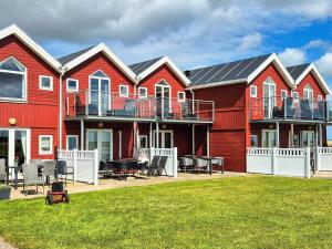 a row of red houses with a lawn in front at 6 person holiday home in Hadsund-By Traum in Hadsund