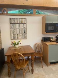 a kitchen with a wooden table and two chairs at Tawny Lodge, Evesham Nr Cotswolds in Evesham