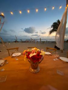 a table on the beach with a vase of flowers at Bambuddha Centro Holistico in Barra Vieja