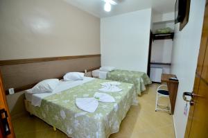 two beds in a hotel room with a chair at Hotel Capital da Fe in Aparecida