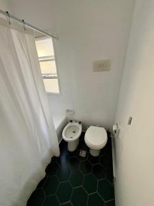a white bathroom with a toilet and a sink at Luminoso Depto al frente en el corazón del barrio Meridiano V- Meridiano Alquiler Temporario in La Plata