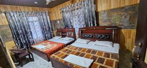 斯利那加Hotel First Kashmir的配有木墙和窗帘的客房内的两张床