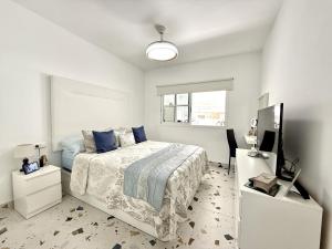 a white bedroom with a bed and a television at Villa Stay & Enjoy in Antigua +29 photos