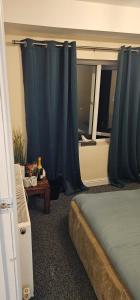 a bedroom with a bed and a window with blue curtains at Sure stay property in Bolton +6 photos