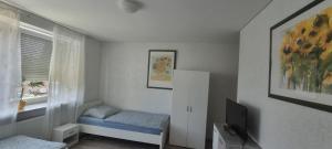 een kleine kamer met een bed en een televisie bij Arzberger Monteurapartment in Arzberg +7 foto's