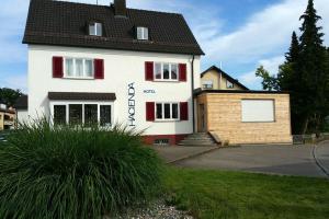 a white house with a black roof and red shutters at Hacienda Rooms in Friedrichshafen