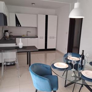 a kitchen with a glass table and blue chairs at Apartments with parking space Slatine, Ciovo - 24699 in Slatine