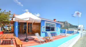 ein blaues Haus mit einer Terrasse mit Stühlen und einem Sonnenschirm in der Unterkunft Villa Nanita in Pláka