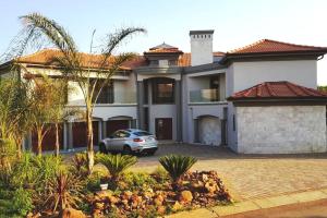 una casa con un coche aparcado delante en The Villa Luxe Hartbeespoort Golf and Wildlife Estate, en Hartbeespoort