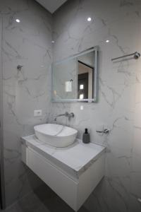a white bathroom with a sink and a mirror at Bujtina Eleni in Himare +182 photos