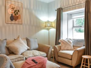 a living room with a couch and a chair and a window at Cottage 2 in Aberdalgie