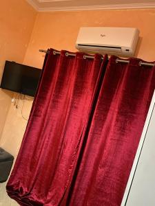 a window with red curtains and a laptop on a wall at Appartement chez Elmehdi in Fès