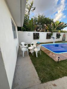 a patio with white chairs and a swimming pool at Centro de Brasília, 5 minutos da Esplanada dos Ministérios in Brasilia