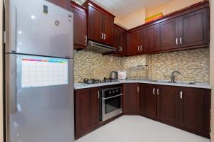 ブンタウにあるThủy Tiên sea view condotelのキッチン(木製キャビネット、ステンレス製の冷蔵庫付)