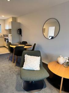 Una sala de estar con una silla y mesas y un espejo. en Plantation apartment, en Wanaka