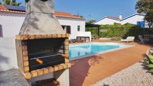 a backyard with a outdoor oven next to a swimming pool at Casa Tucano in Aljezur
