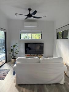 a living room with a white couch and a ceiling fan at Cute and cosy 1 bedroom cabin in Mooloolah