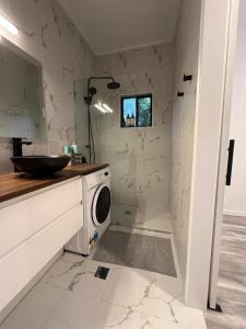 a bathroom with a sink and a washing machine at Cute and cosy 1 bedroom cabin in Mooloolah