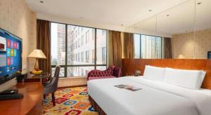 Pokój hotelowy z dużym łóżkiem i biurkiem z telewizorem w obiekcie Oriental Glory Hotel w mieście Dongguan