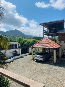 une voiture garée sous un kiosque devant une maison dans l'établissement Villa de Grupo 16, Piscina Natural, Jacuzzi, Granja y Mascotas, Rosa & Deivi te esperan, à Villa Altagracia