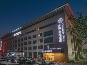 a large building with cars parked in a parking lot at Chonpines Hotel Jining Quanmin Fitness Plaza in Jining