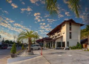 a building with a palm tree in a parking lot at The La-Ngu Boutique in Satun