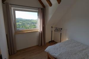 a bedroom with a large window and a bed at Chata w Bieszczadach ,,Słońce i Cień" PIĘKNE WIDOKI in Baligród