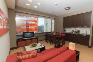 a living room with a red couch and a kitchen at Hausuites in Mexico City