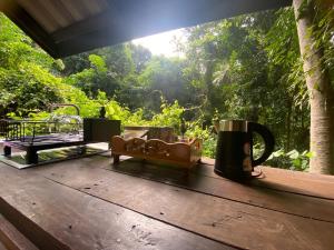 een veranda met een tafel met een koffiemok en een bankje bij Singing Frogs Jungle Stay in Ban Lamai +21 foto's