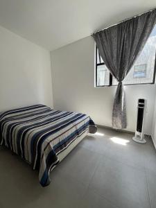 a bedroom with a bed and a window with curtains at Departamento nuevo completo Zoologico GDL in Guadalajara