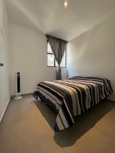 a bedroom with a bed with a striped blanket on it at Departamento nuevo completo Zoologico GDL in Guadalajara