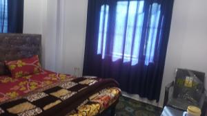 a bedroom with a bed and a window with curtains at Kanha Homestay and restaurant in Dhanaulti