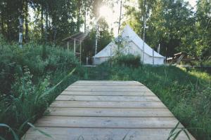 a wooden path in a field with a building in the background at Slow Life Sweden - Family Glamping Tent Poppel 