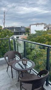 a glass table and two chairs on a balcony at Тони апартмент in Burgas City